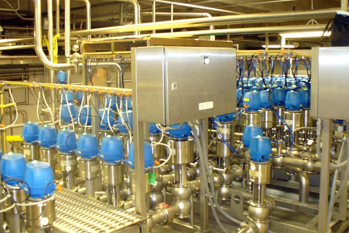 Valve manifold with blue actuators beside stainless control boxes