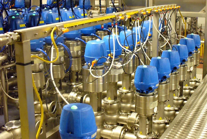 Stainless process piping manifold with blue valve actuators, built by Expert Tool & Machine